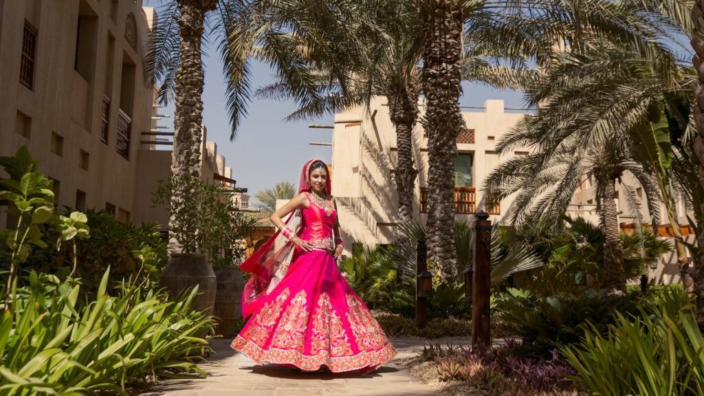 Bride in vivid pink wedding attire in a garden setting