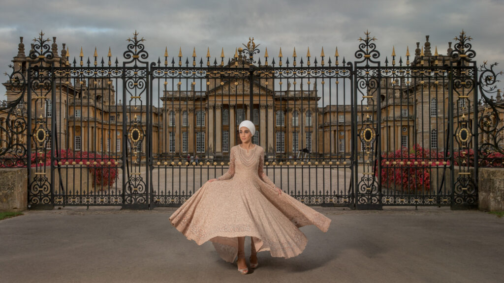 Bride in a wedding gown by ornate estate gates